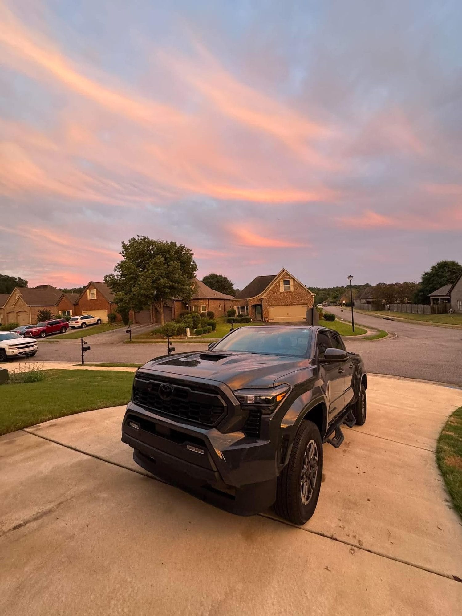 Dark grey Toyota Tacoma on a driveway at sunset