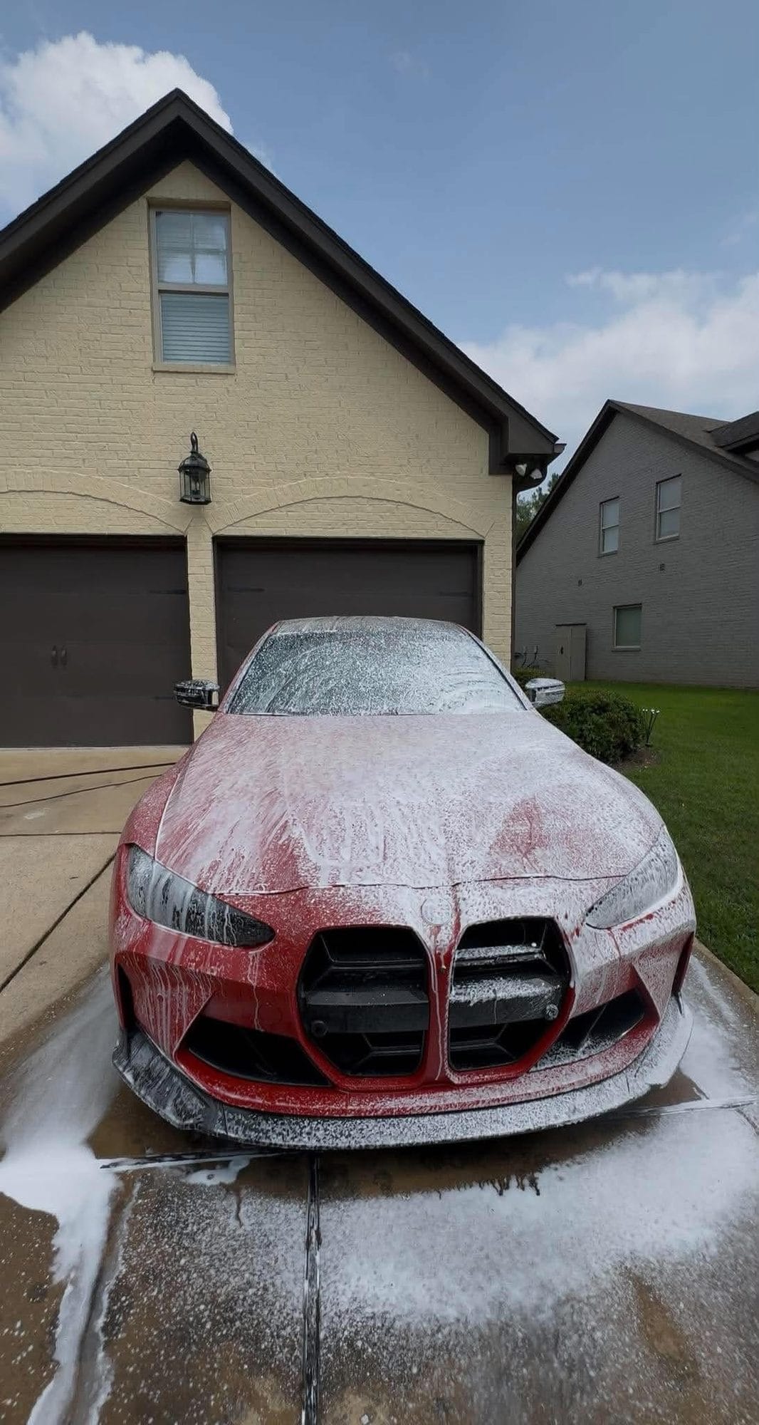 Red BMW M4 covered in foam during a hand wash