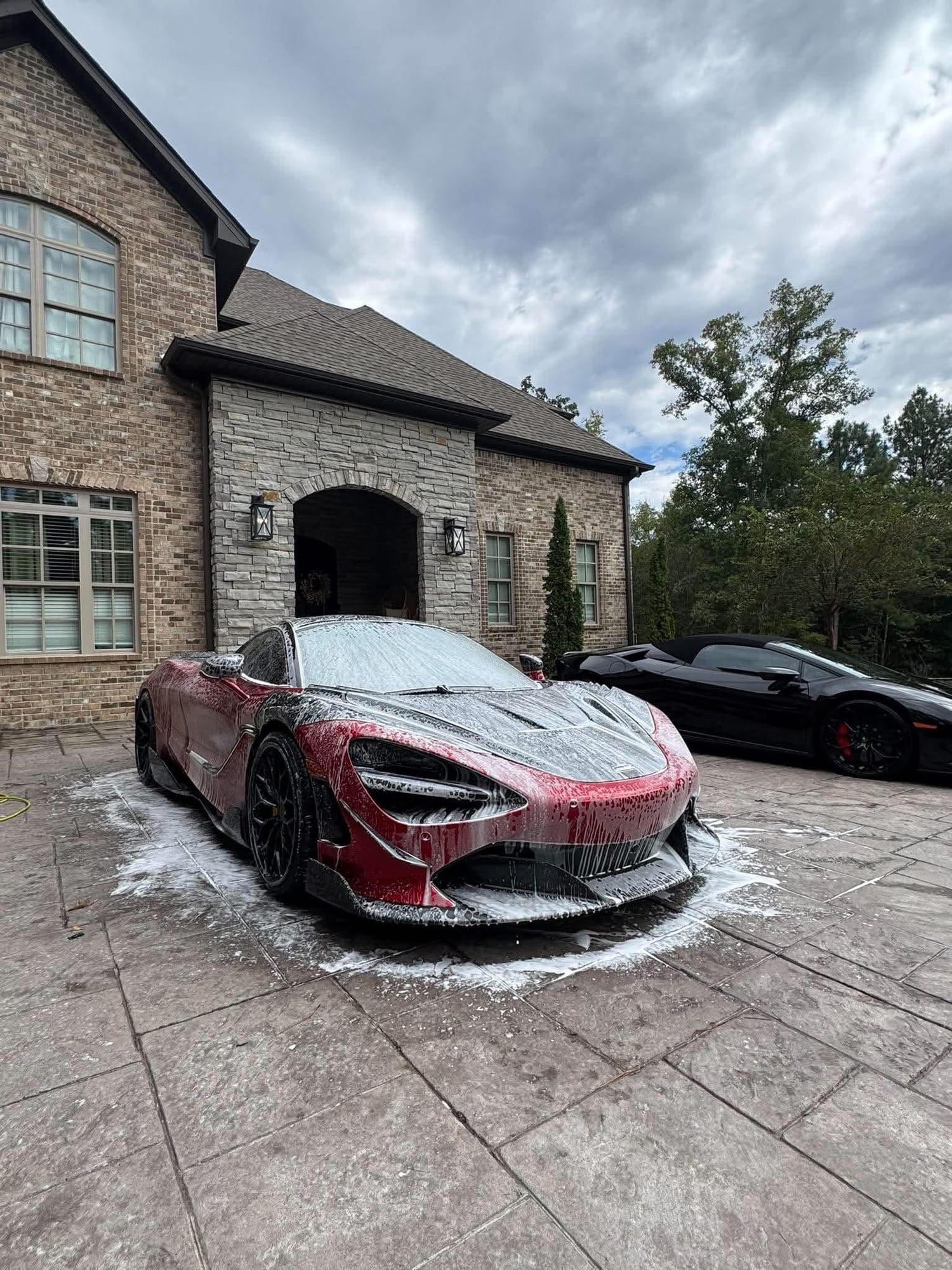Red McLaren covered in foam during a hand wash